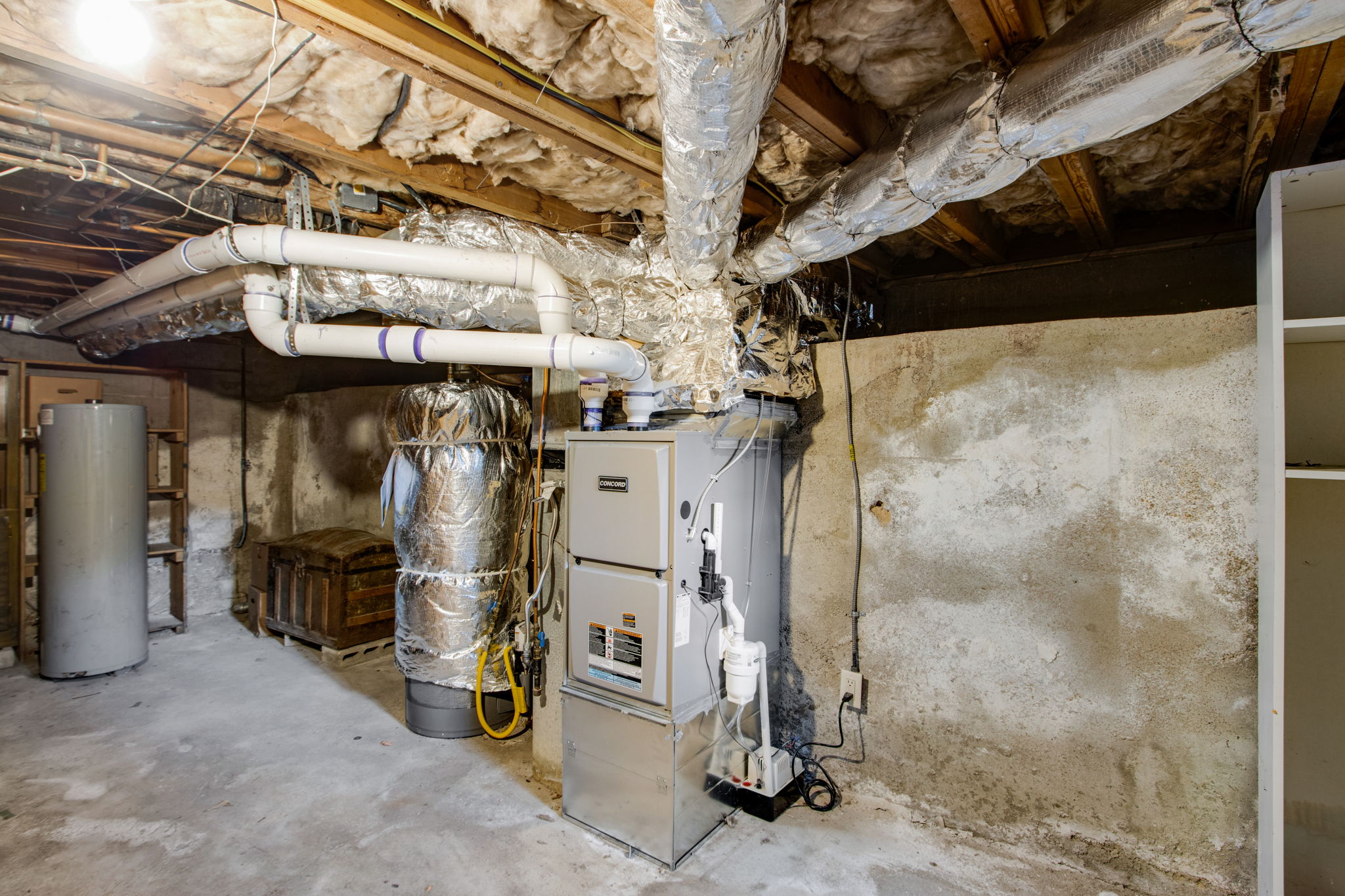 A residential furnace and insulated ductwork in a basement heating and cooling system