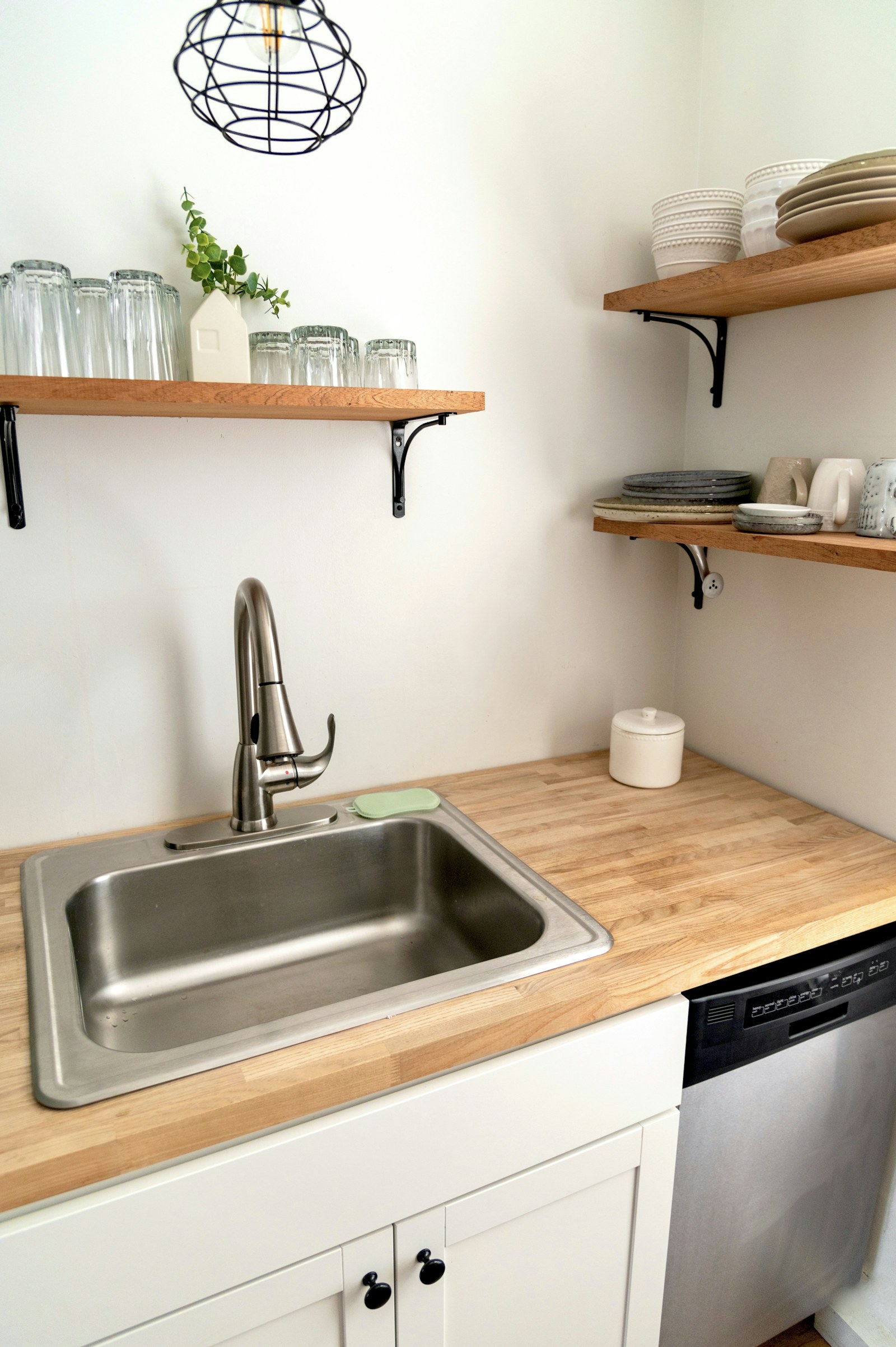 A stainless steel kitchen sink and pull-down faucet on a wood countertop