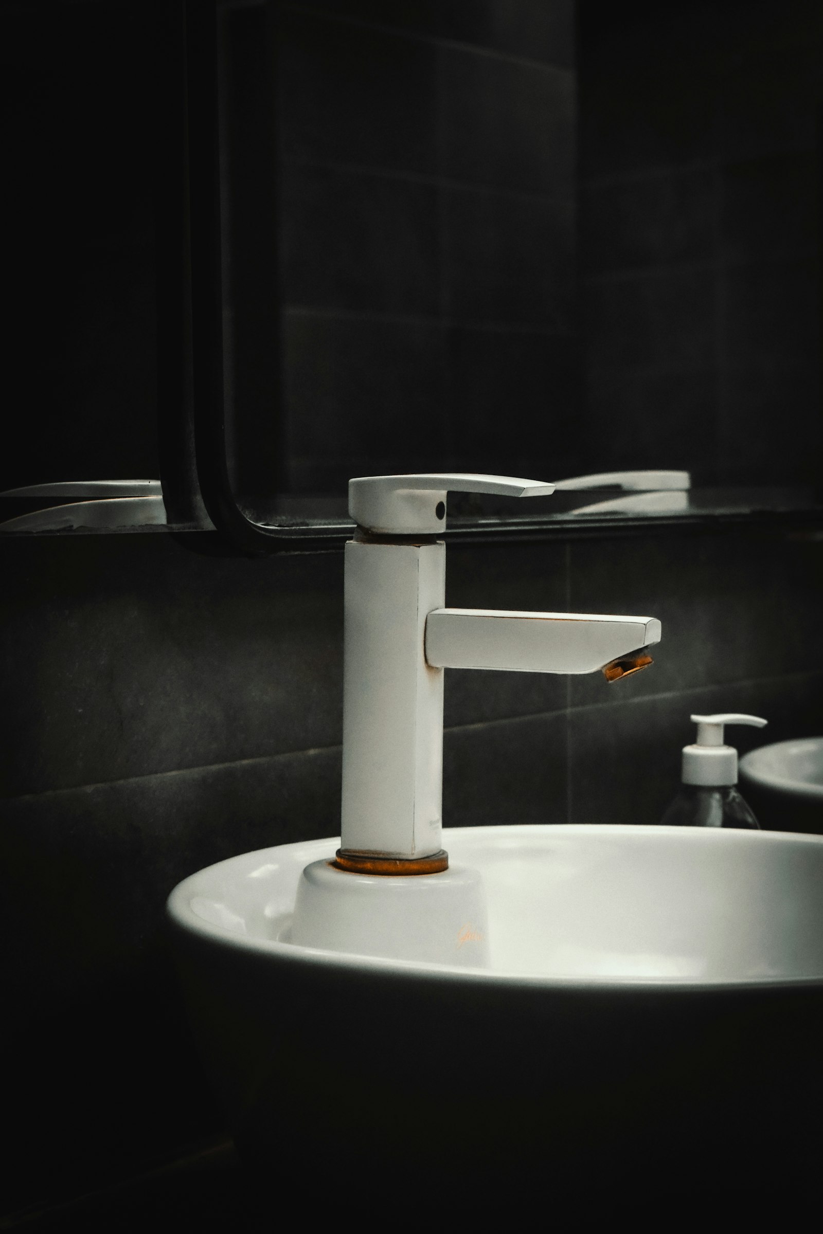 A white bathroom faucet and basin, showing fixtures serviced or replaced in residential plumbing